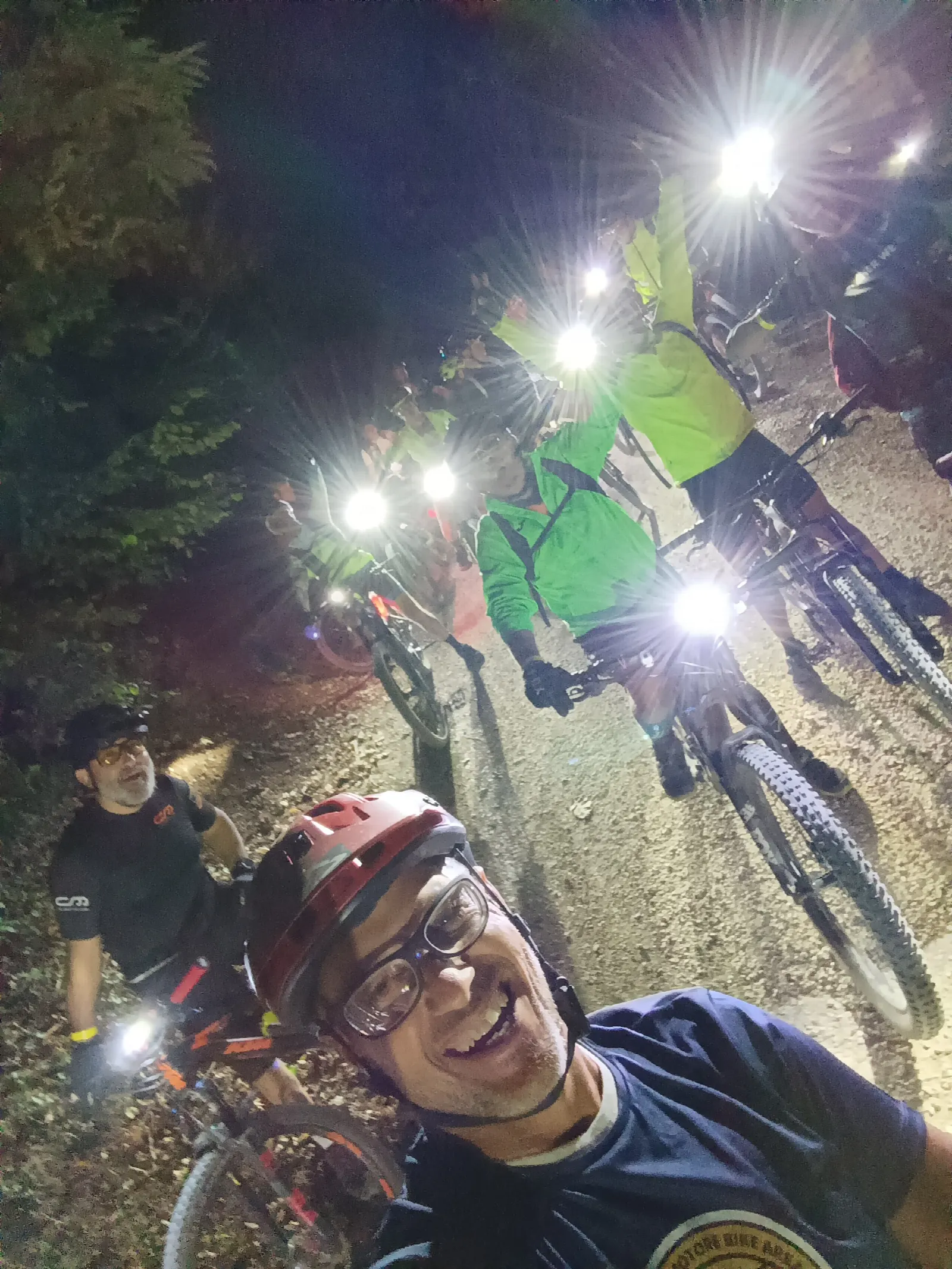 Biker con le luci accese nel bosco al calar della sera durante la cicloturistica notturna