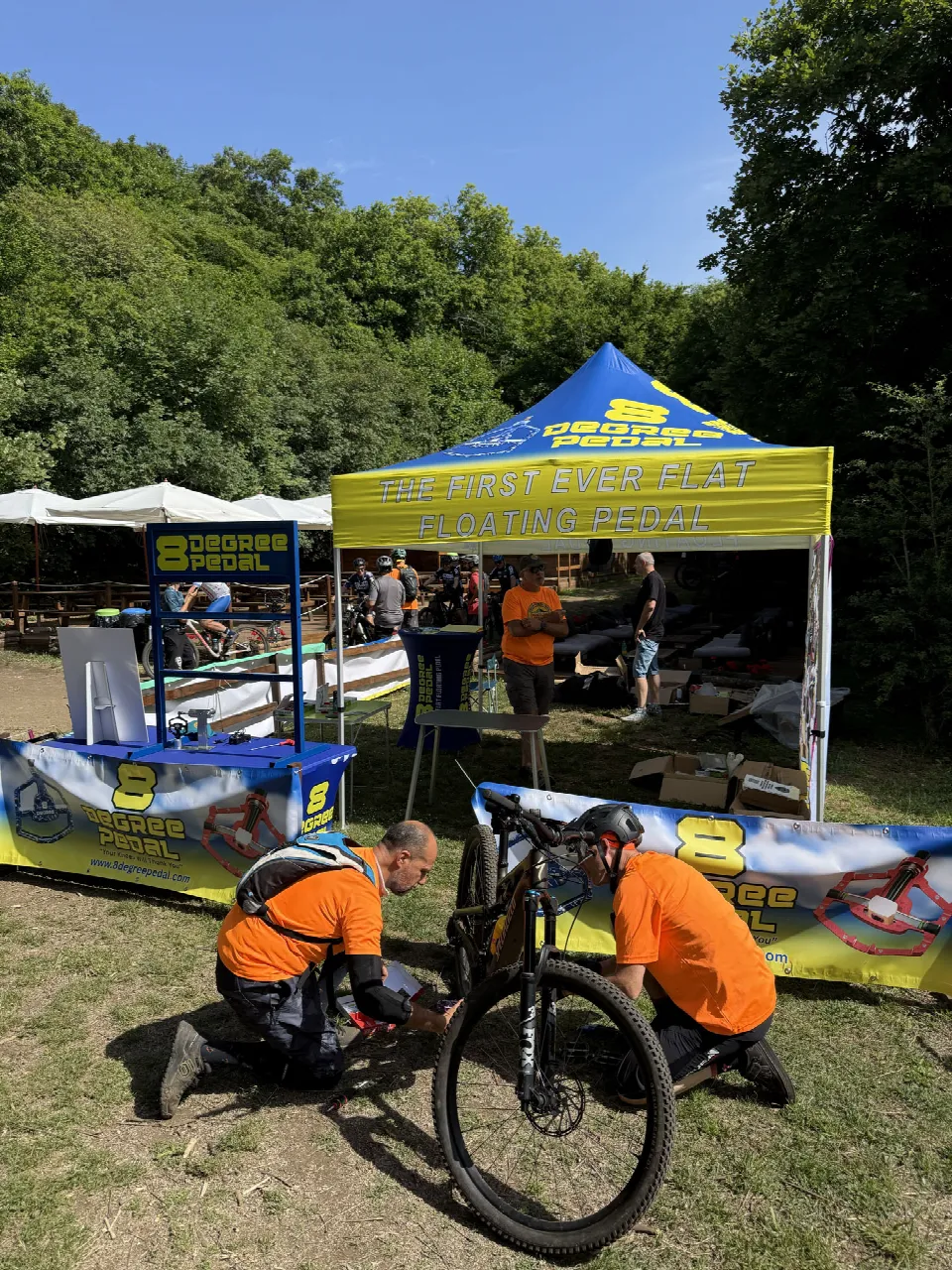 Soci dell'ASD montano i pedali di prova su una bici sotto il gazebo di 8 Degree Pedal