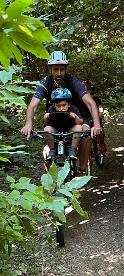 Un biker con un bambino sul seggiolino lungo un sentiero nel bosco