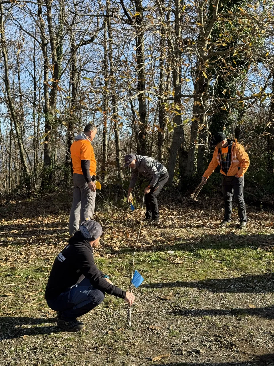 Partecipanti al corso IMBA che tracciano un sentiero nel bosco con le bandierine